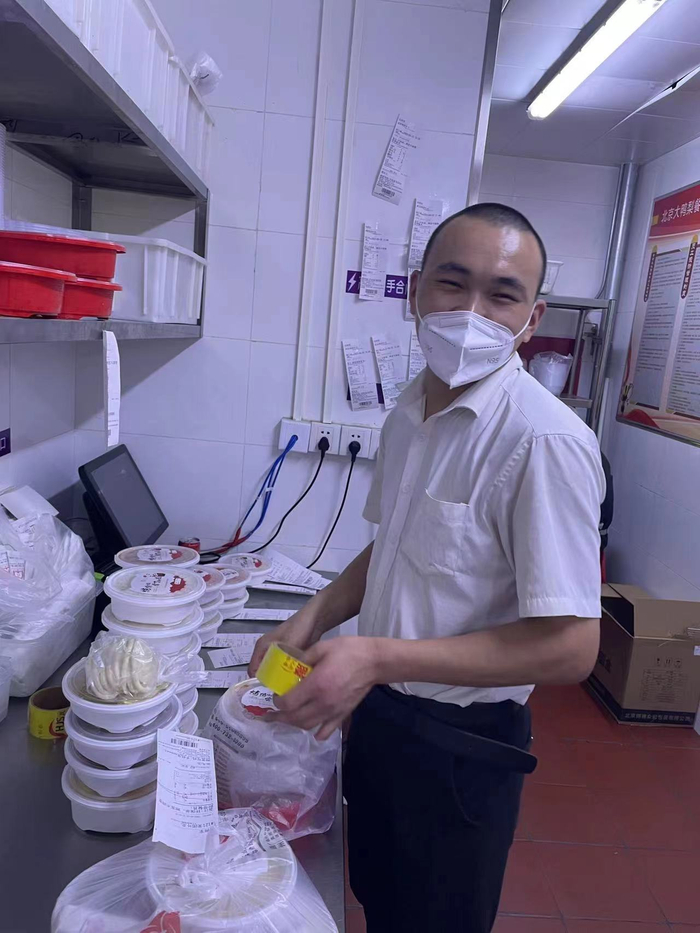 张志龙在餐厅后厨帮忙打包外卖。受访者供图