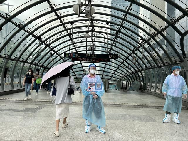 世纪大道站12号出入口，有专人持场所码的牌子，提醒乘客配合扫码进站。澎湃新闻记者陈逸欣 图