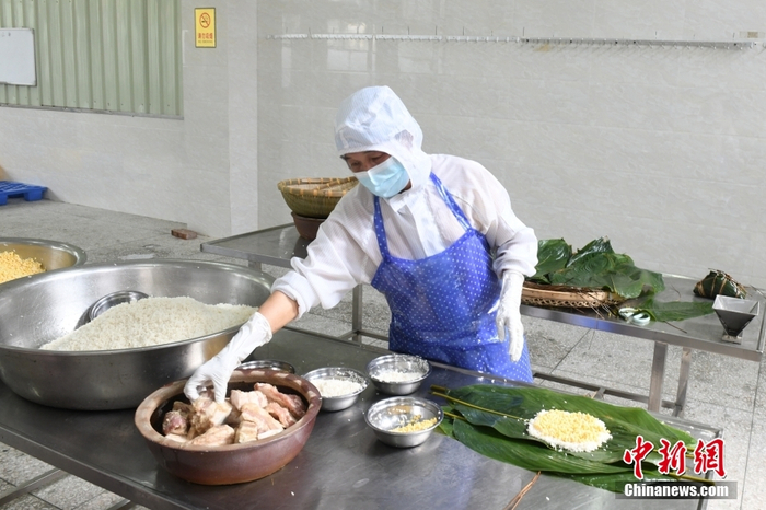 图为5月26日，包粽师傅将腌制五花肉放入大粽内。   中新社记者 林浩 摄