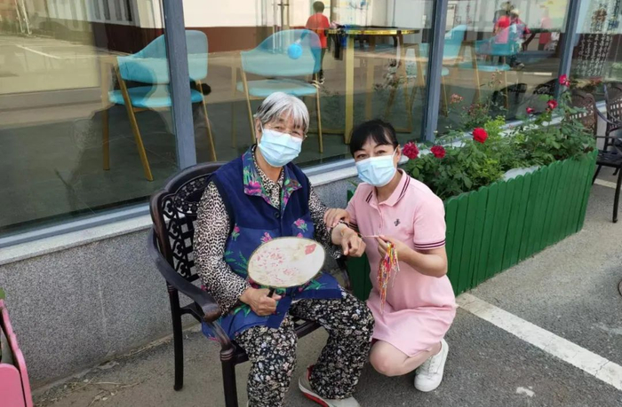 ▲端午节时，院长徐久华（右）为老人系五彩绳送平安。受访者供图