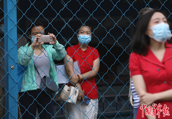     6月7日，北京市朝阳区陈经纶中学考点外，家长隔着防护网拍照。中青报·中青网记者 陈剑/摄