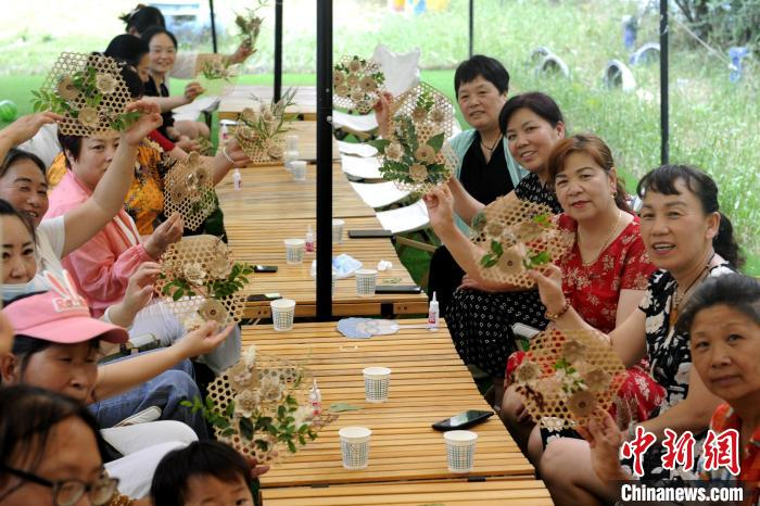 图为来乔村游玩的民众与当地妇女共同展示制作成功的手工艺品。　高铖 摄