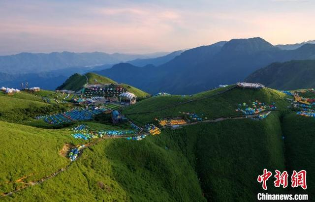 图为晨光逐渐洒向了江西武功山绿意盎然的万亩高山草甸以及山顶上的各色帐篷，风景秀美。 肖南波 摄 