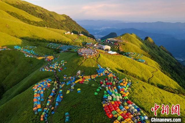 图为金色光芒洒向了江西武功山绿意盎然的万亩高山草甸以及山顶上的各色帐篷，不少游客正在欣赏日出美景。 刘芸池 摄