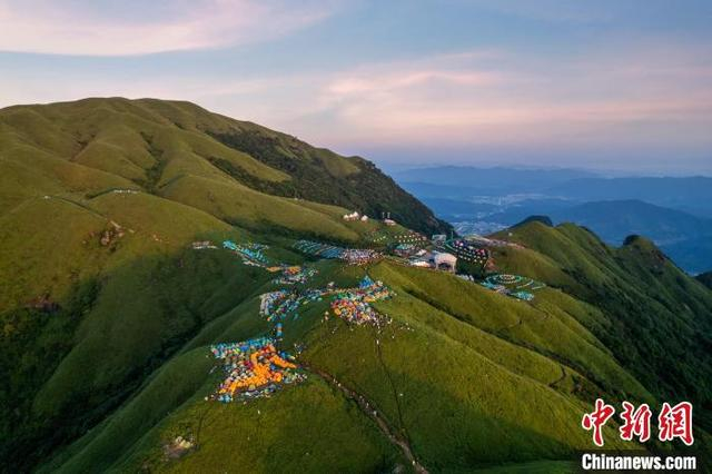 图为晨光洒向了江西武功山绿意盎然的万亩高山草甸以及山顶上的各色帐篷，风景秀美。 肖南波 摄 