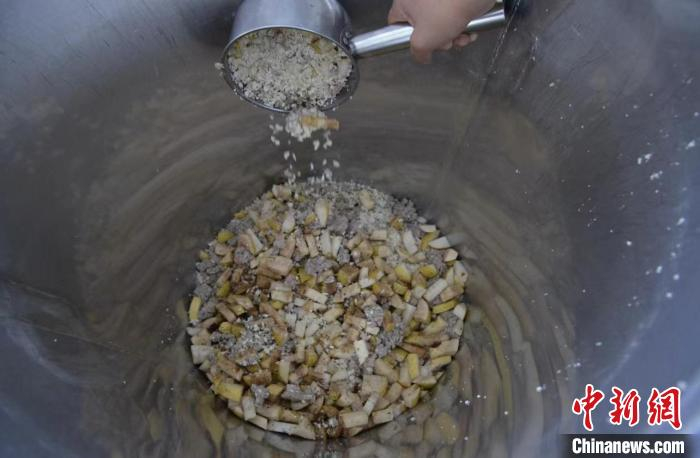 工人正将羊肉、雪花梨、杏仁等混合搅拌的原料倒入发酵酒器。　李明发 摄