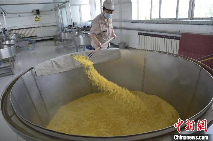 工人正将浸泡好的黍米撒在蒸锅内准备蒸米。　李明发 摄