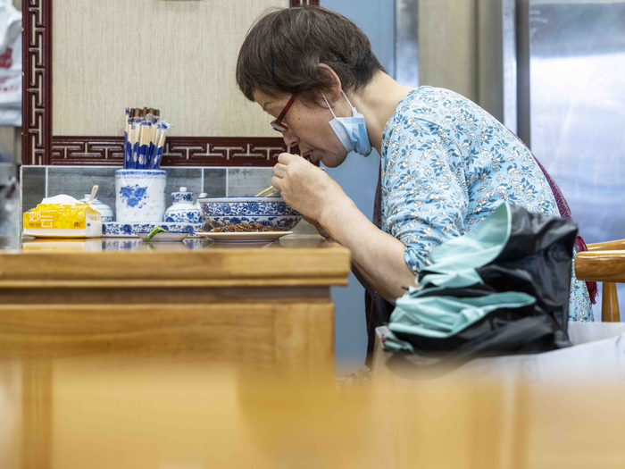 2022年6月29日，上海愚园路，一老人在认真吃面。许海峰 图