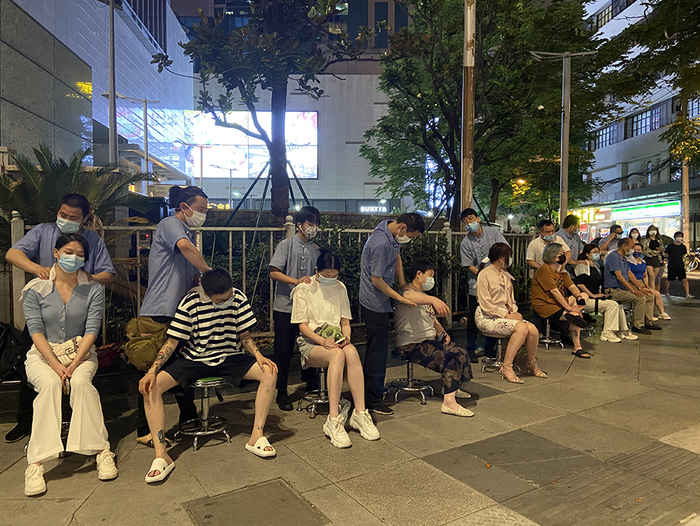 6月20日晚，按摩师在街头进行肩颈按摩。除标注外，本文图片均为澎湃新闻记者 陈悦 图