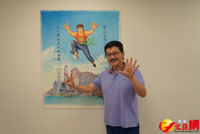 黄玉郎举起双手，模仿着画作中角色的手势。 图片来源：香港文汇网