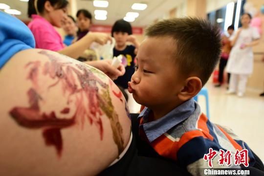 资料图：孩子亲吻妈妈的肚皮。钟欣 摄