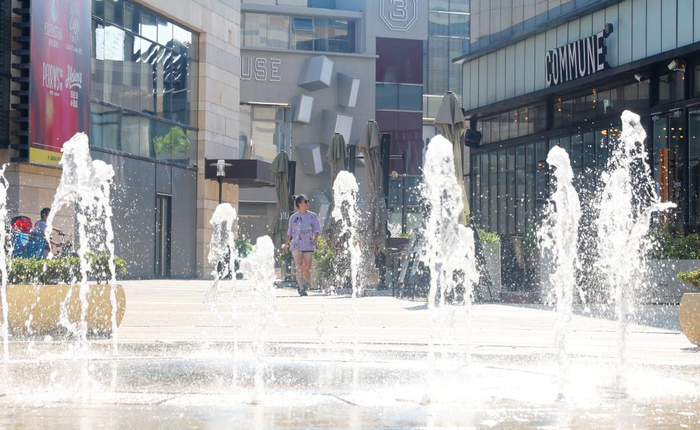 　　7月10日，一位市民走在上海闵行区一家商场外的喷泉前。新华社记者 方喆 摄