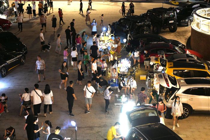 车主们在后备厢里摆放着琳琅满目的自制产品吸引游客挑选购买。