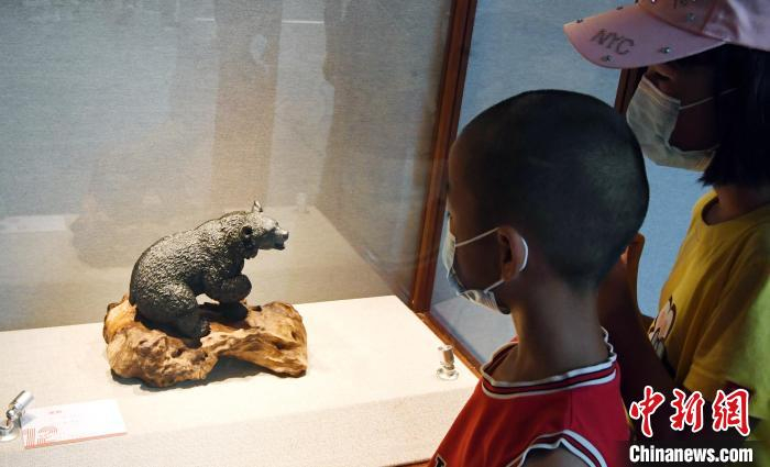 由中国工艺美术大师林亨云创作的寿山石雕刻作品《黑熊》吸引孩子们观看。　记者刘可耕 摄