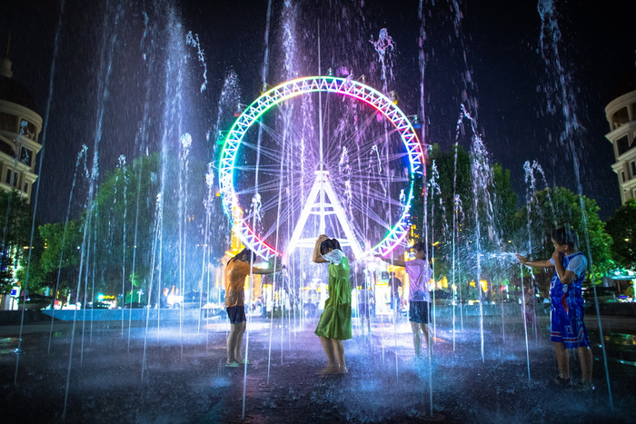 7月2日，小朋友在武汉汉口北夜市的喷泉边玩耍。