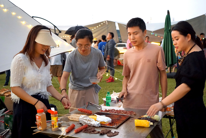 2022年7月8日，浙江金华，入驻武义县大斗山飞行营地草坪露营夜市的摊主现做现卖各种特色美食。
