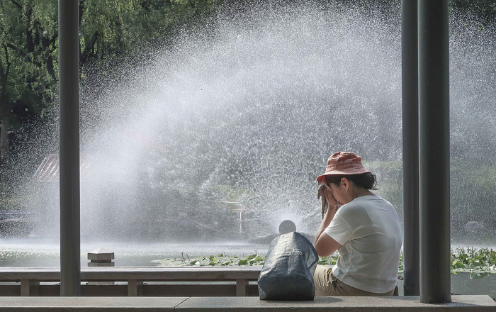 2022年7月14日，上海，在徐家汇公园，一位游客不停地擦汗。人民视觉&nbsp; 图