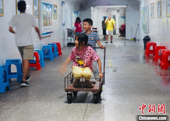 7月16日，广西柳州马鞍山人防工程1号纳凉点，孩子从此经过，躲避烈日。　李娇阳 摄