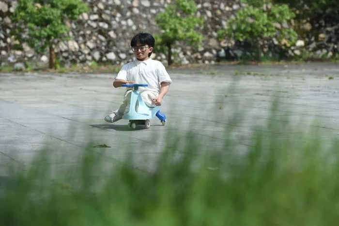 张亮驾着扭扭车在校园里&nbsp; 新华社记者 周牧 摄