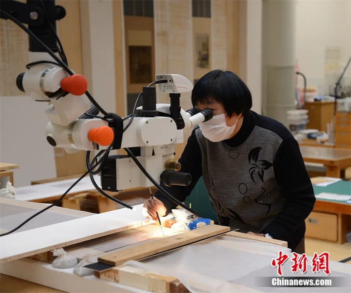 邱锦仙借助放大镜添浆修复《女史箴图》。大英博物馆托管会供图