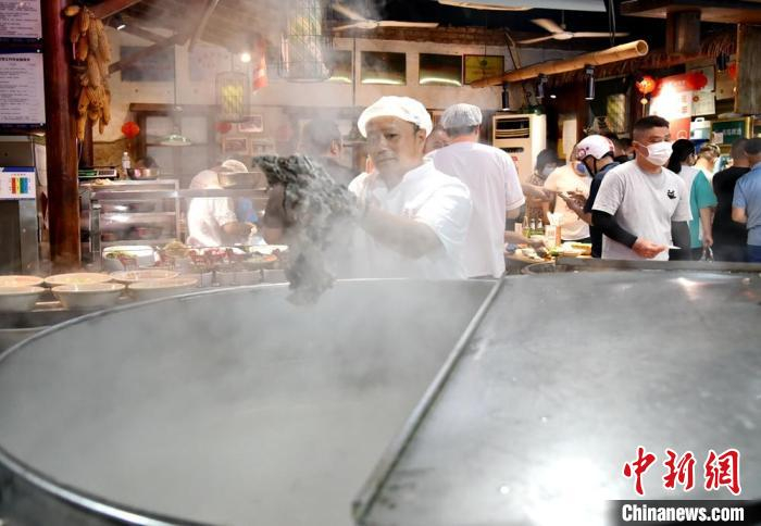 厨师从直径1.5米的大锅里捞出煮好的大块羊肉。　朱志庚 摄