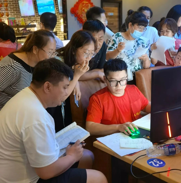 ▲7月15日，呼和浩特一家网吧内，穿着印有“金榜题名”字样红色工作服的操盘手正在帮一位考生填报志愿。新京报记者 李照 摄