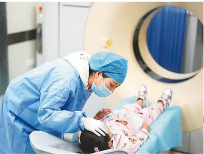 不久前，来自西藏拉萨的23名先天性心脏病小患者在南京医科大学第二附属医院分批接受免费手术治疗。图为5月12日，护士在安慰准备接受CT增强检查的小患者达瓦卓玛。新华社记者 季春鹏摄