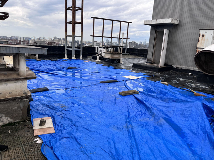 屋顶有人用塑料布挡住应急