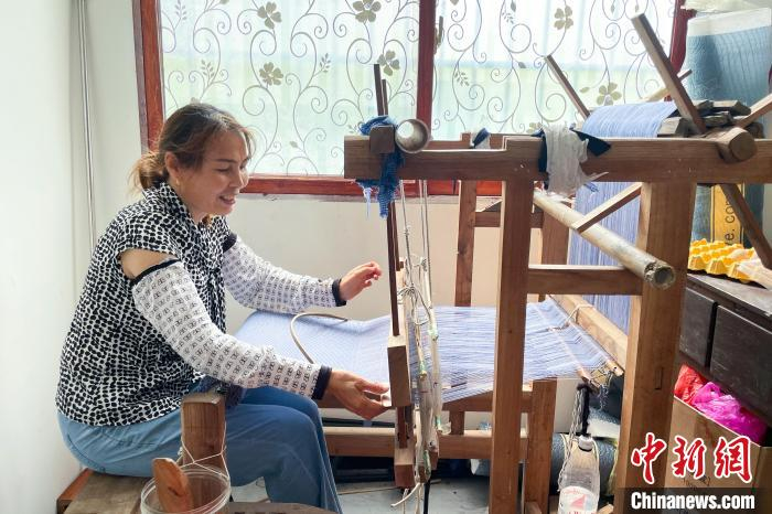 图为下甲镇彩架村村民罗凤琼正用传统织布机制作当地特色布料。　王伟臣 摄
