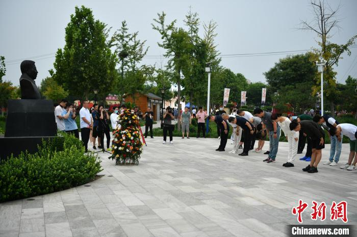 图为该电影主创人员向闫胜联雕像献花篮并鞠躬。　翟羽佳 摄