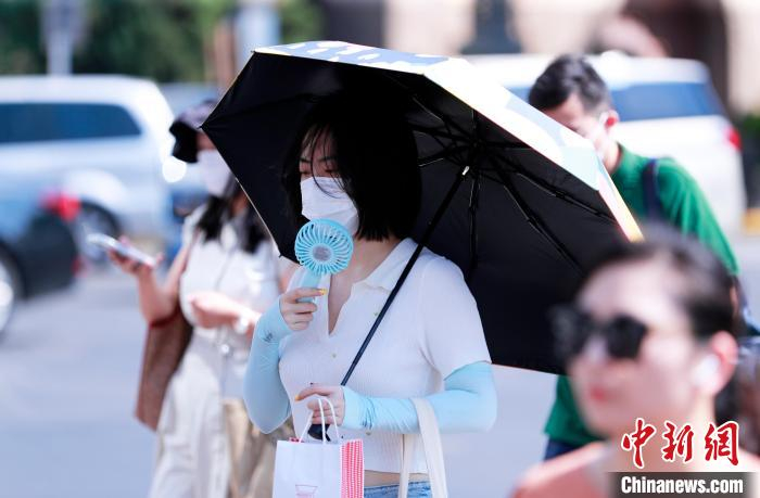 市民自带风扇降温消暑。　汤彦俊 摄