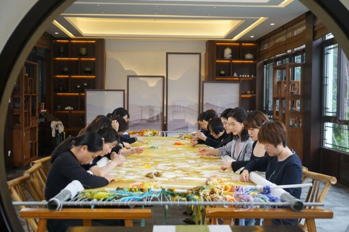 △姚建萍和女儿，与团队成员共同创作苏绣作品。