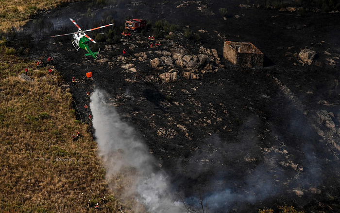 当地时间2022年8月11日，葡萄牙埃什特雷拉山自然公园，一架直升机向山火洒水。