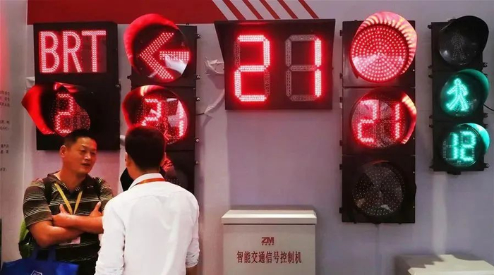 ▲第十三届中国国际智能交通展览会上，一名参观者（左）与展方工作人员在一组交通信号灯展品前交谈。图/新华社