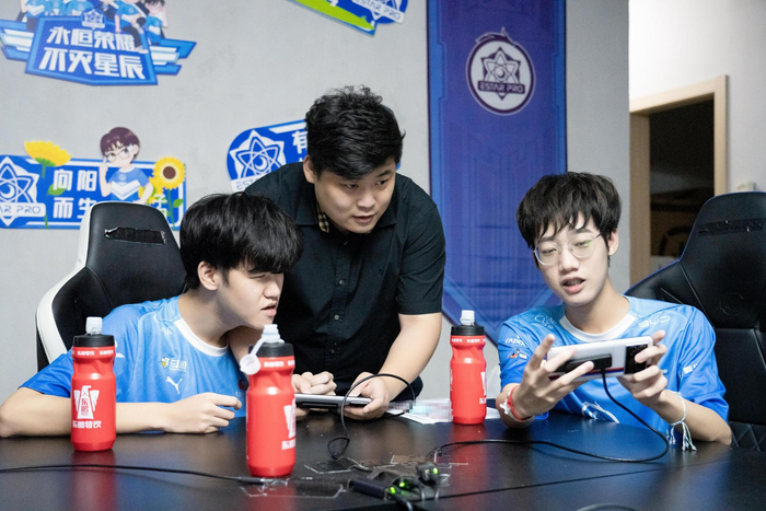 黄垚钦（右）与队友、教练探讨战术。  武汉eStarPro俱乐部供图