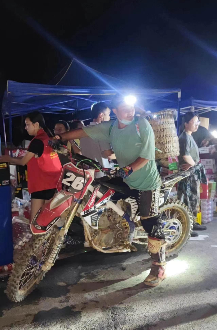 ▲8月22日晚，重庆市北碚区歇马街道虎头村，车手龙杰戴着头灯，准备向山上运送物资。 受访者供图