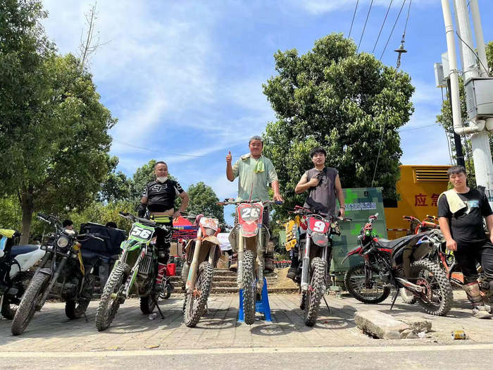 ▲8月23日上午，龙杰（图中）的摩托车油门线损坏，在等待修车师傅赶来的间隙，与几位正在休整的摩友合影。 受访者供图
