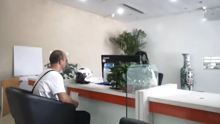 一名摩托车主在焦作市一家保险公司内与保险公司工作人员协商投保事宜。国务院大督查第九督查组供图