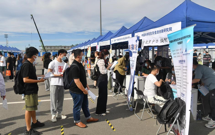 学生们在提供北京户口、编制等优厚条件的企业展台前投简历。 新京报记者 李木易 摄