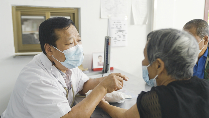 ▲2022年8月，朱来成在诊所给村里老人把脉、量血压。&nbsp; 新京报记者 孙霖婧 摄