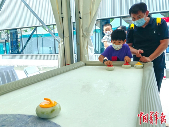     8月，北京，2022年全国科技活动周暨北京科技周活动主场，小朋友玩的桌上冰壶的冰面是用“凝胶冰雪”技术打造的。陈鼎/摄
