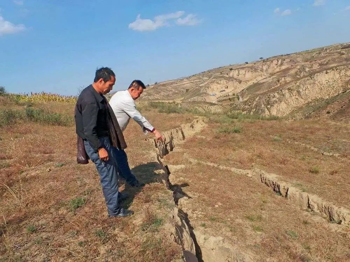 横山区白岔村村民，指向当地煤矿过度开采造成的地表塌陷地段。图源：中国新闻周刊