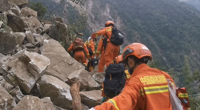 通往受灾村落的道路被巨石拦住，消防员从巨石间狭窄的空隙间穿过。受访者供图