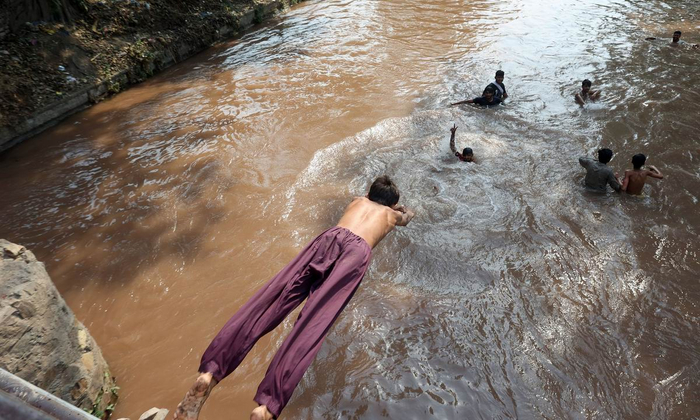 当地时间2022年5月7日，巴基斯坦拉合尔，当地遭遇高温天气，人们跳入运河中解暑。