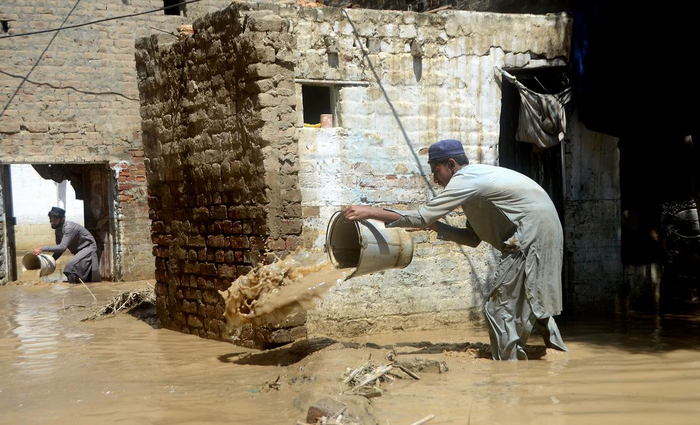 当地时间2022年8月28日，巴基斯坦贾尔瑟达，一名男子倾倒房子里积水。