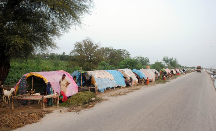 当地时间2022年8月27日，巴基斯坦信德省，当地发生山洪，人们在路边临时搭建帐篷。