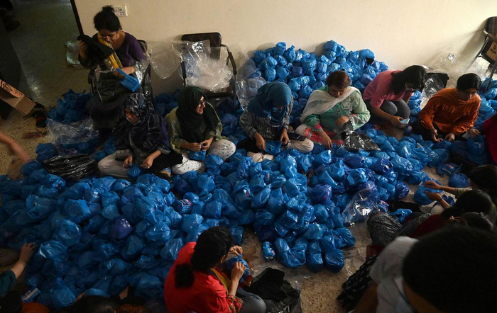 当地时间2022年8月31日，巴基斯坦拉合尔，非政府组织的成员正在为因大规模洪水而流离失所的妇女打包提供卫生巾。