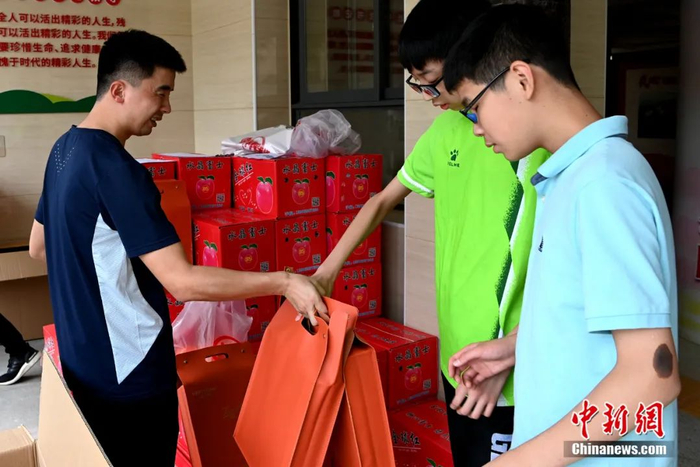 在盲校里，王亚锋除了给学生上足球课，也做一些后勤工作，图为王亚锋给盲校学生发放爱心人士捐助的中秋节礼品。王东明 摄