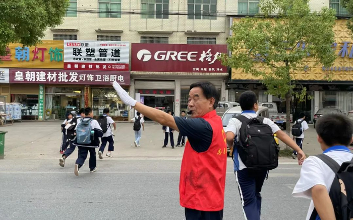 ▲汤其雪在学校门前的路口疏导车辆护送学生。受访者供图