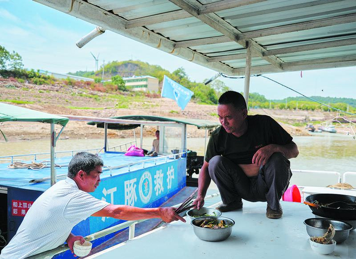 9月7日，忙碌了一上午的占柏山与队员们在巡护船上吃饭。新京报记者 郭延冰 摄
